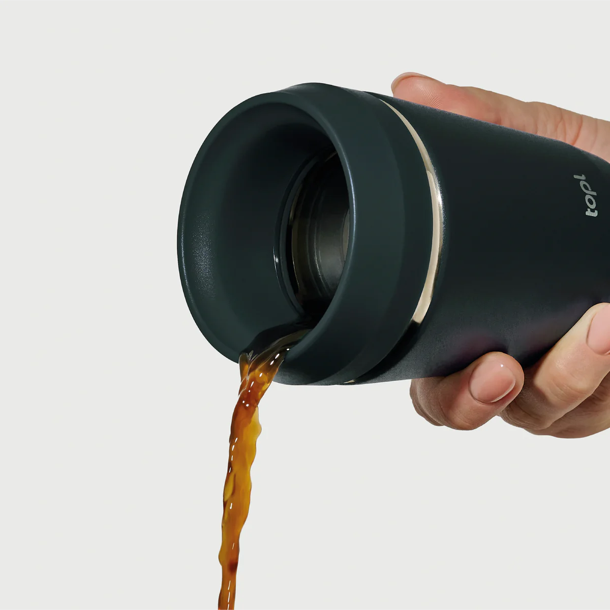 Hand pouring coffee from Hedoniq charcoal (black) travel cup by TOPL, designed for spill-proof convenience.
