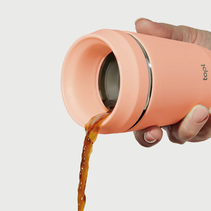 Hand pouring coffee from Hedoniq peach travel cup by TOPL, designed for spill-proof convenience.